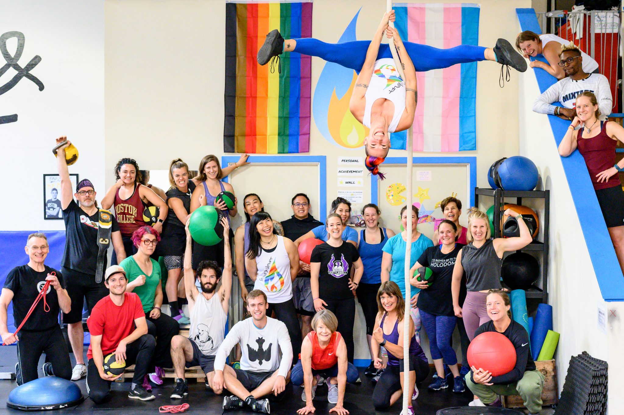 Strive & Uplift coaches and community pose in front of intersectional pride flags.